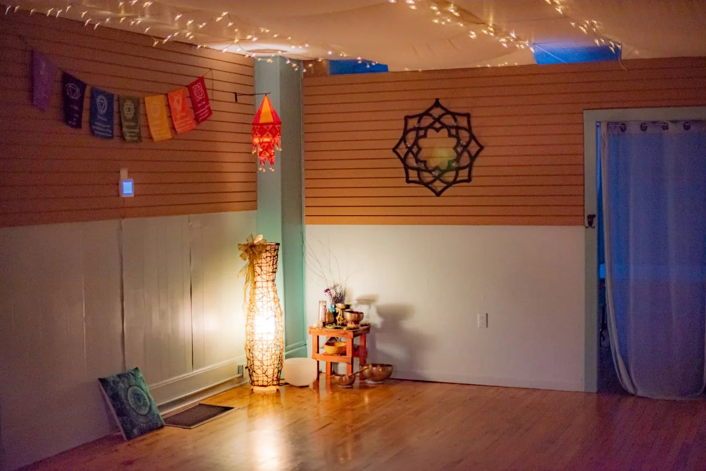 A cozy corner of the studio with a salt lamp, singing bowls, and chakra flags